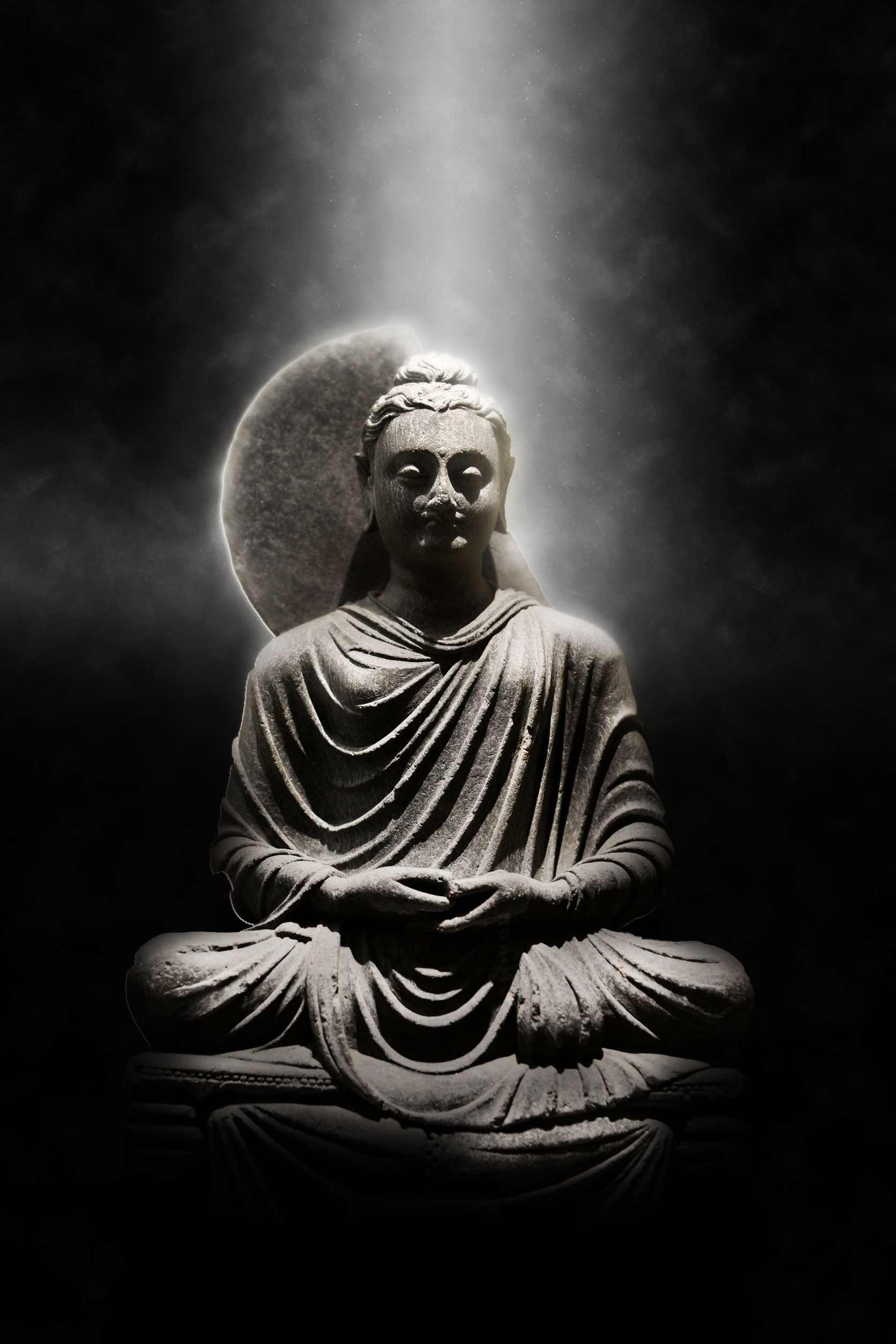 41026822 - full length stone carved seated buddha statue dramatically lit from above on dark background, meditation and spirituality concept still life image